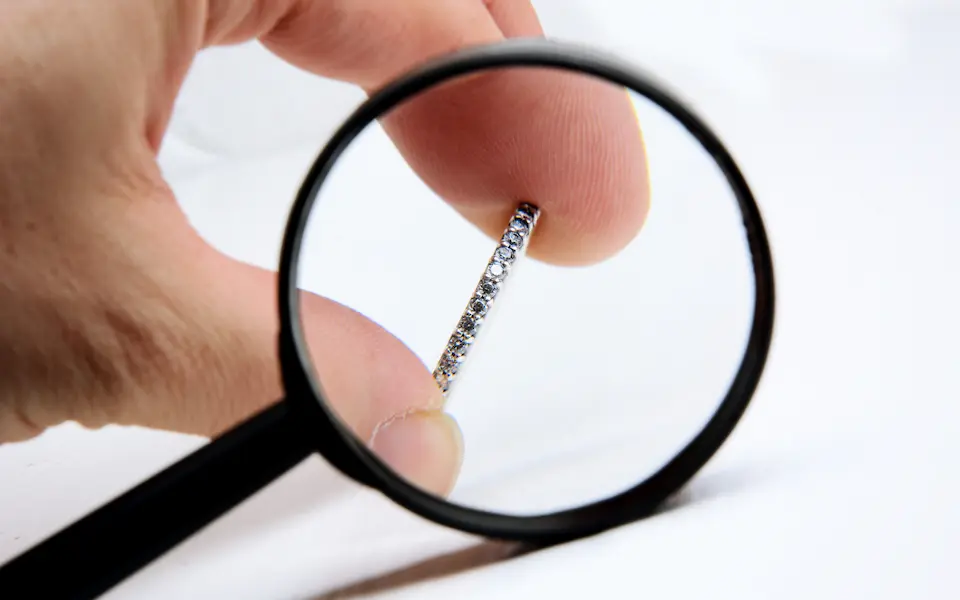 Diamond ring being appraised with the help of a magnifying glass