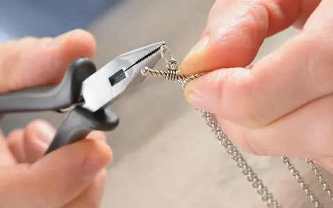 Zoom in a Jeweler's  hands while repairing a silver chain